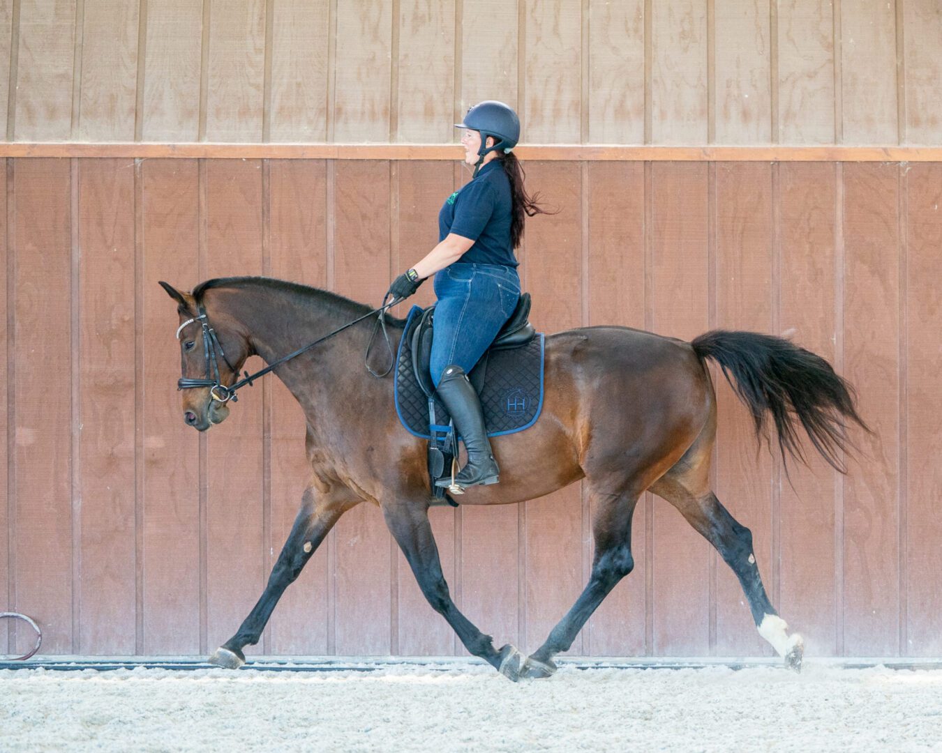 Woman riding brown horse in indoor arena