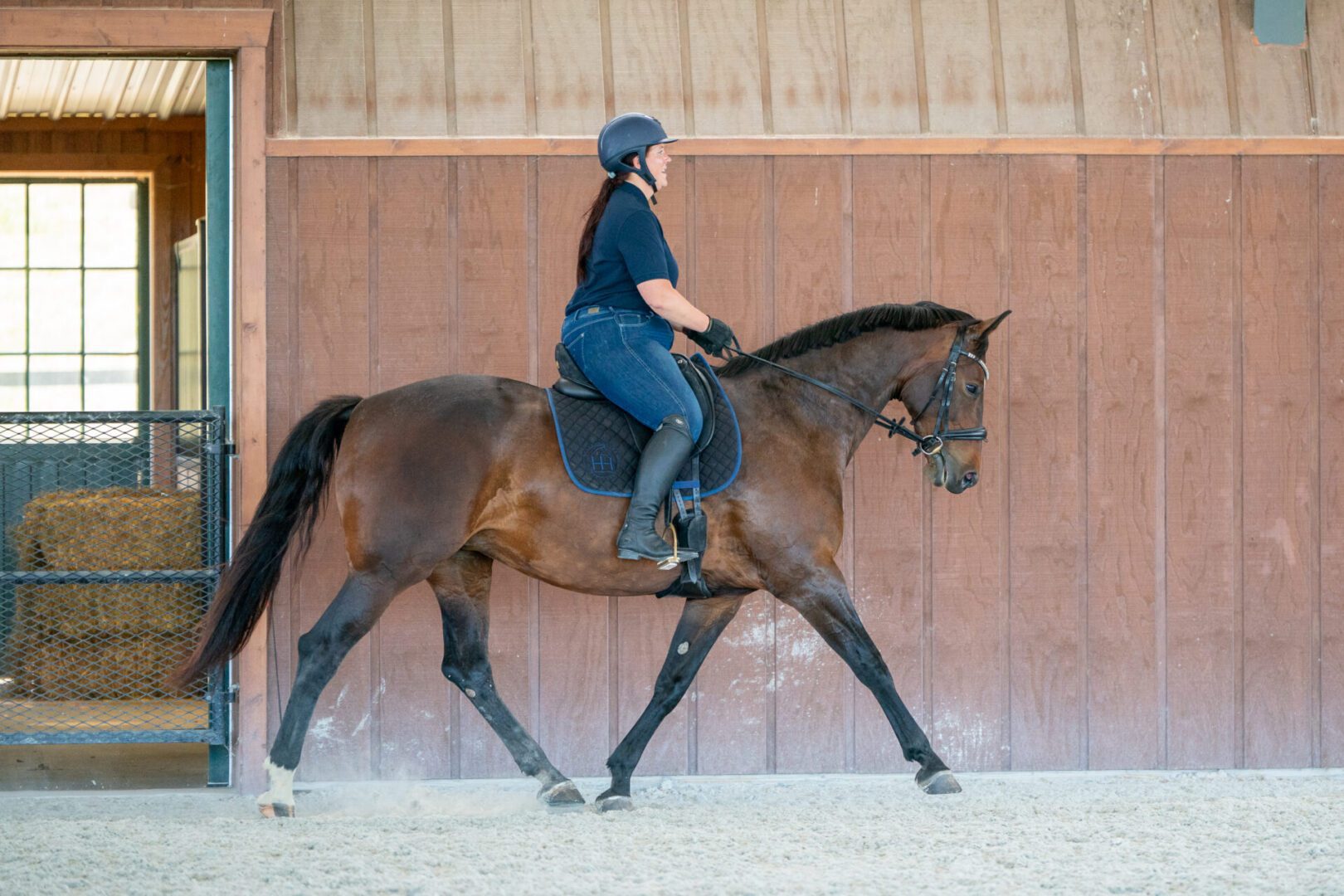Woman riding bay horse in indoor riding arena